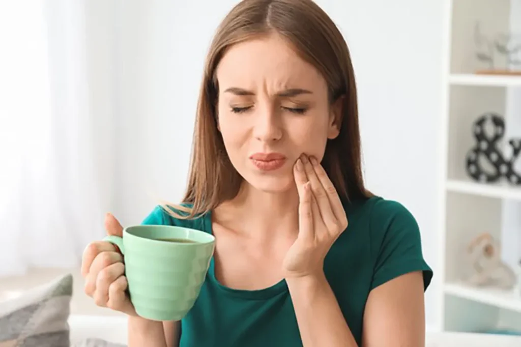 Woman wincing with tooth sensitivity pain